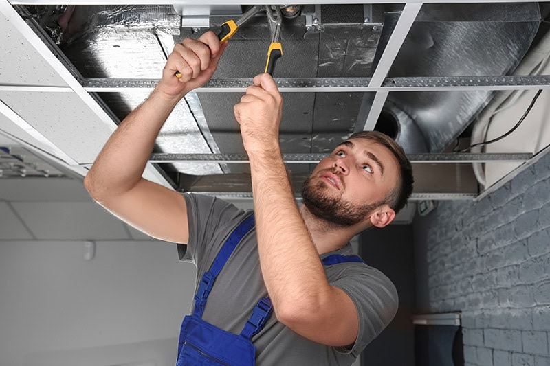 Male technician repairing air conditioner indoors, Does SEER Save Money? | HVAC Energy Efficiency | Sutton Brothers