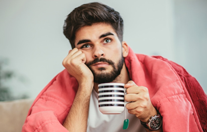 Bearded man wrapped in red blanket holding a cup of tea | Why Isn't My Furnace Heating My Entire Home? | Winston-Salem, NC