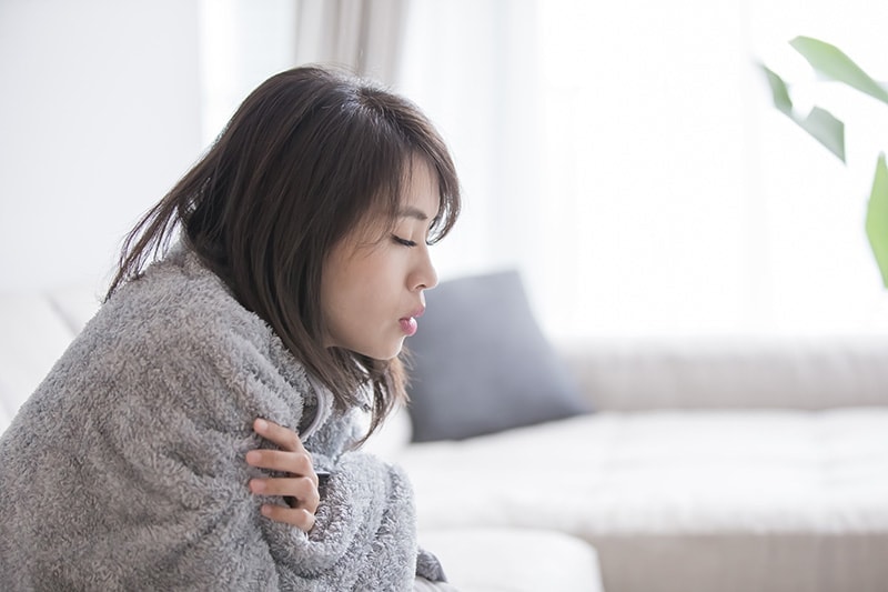 Woman cold indoors wrapped in blanket, Why Is My Furnace Blowing Out Cold Air? | HVAC | Winston-Salem