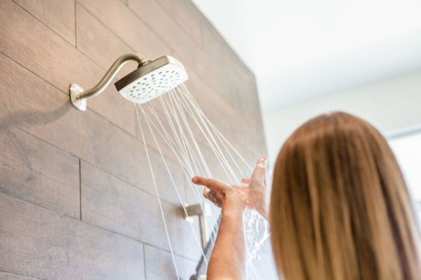 Image of someone testing water from showerhead. No Hot Water? 5 Causes and What to Do.