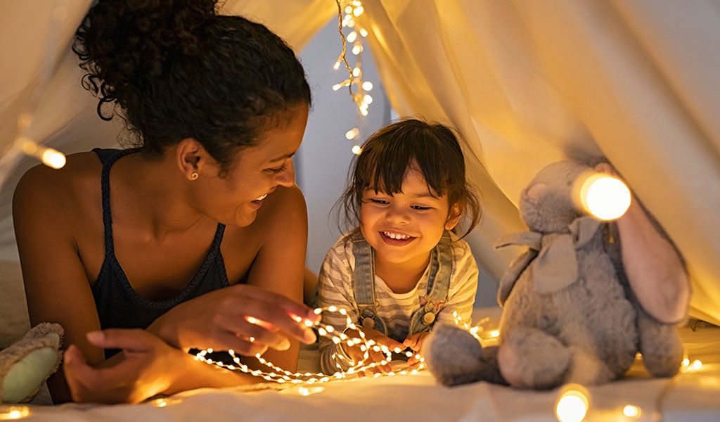 Mother and daughter playing at home in tent