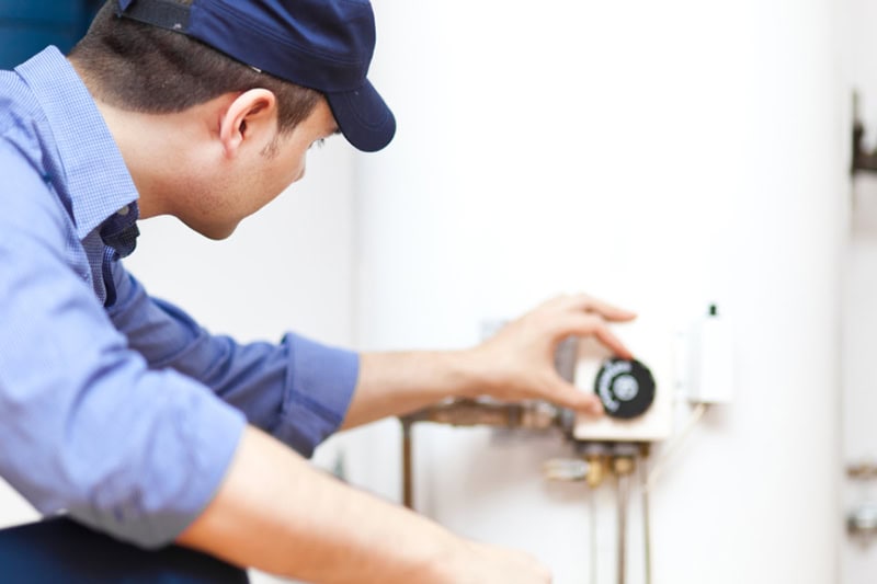 Signs Your Water Heater Needs Repair. Smiling technician repairing an hot-water heater.